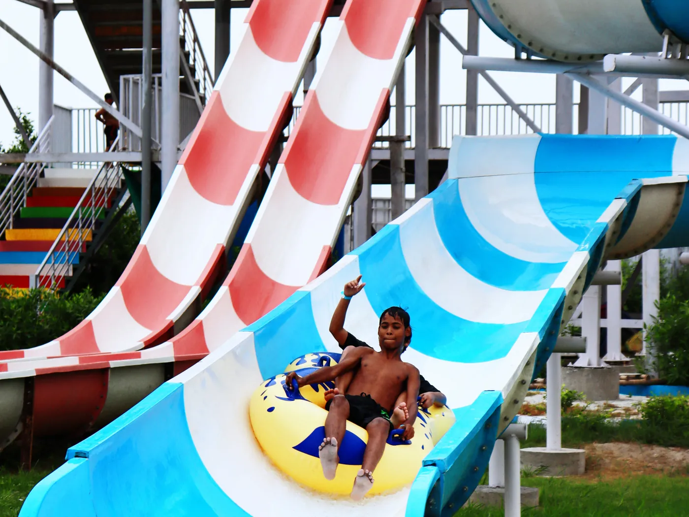 A rider coming down the open blue water slide on a tube